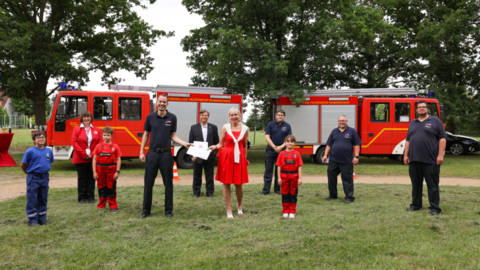 Digitalministerin Kristina Sinemus überreicht Feuerwehrvorsitzendem Kevin Schmittinger den Förderbescheid