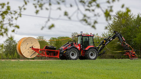 Traktor beim Glasfaserausbau in einer grünen Landschaft