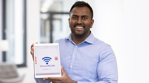 Person hält Tablet mit HessenWLAN-Logo Person hält Tablet mit HessenWLAN-Logo