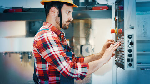 Mann an Bedienfeld einer Maschine