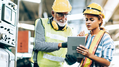 Zwei Arbeiter schauen auf ein Tablet Zwei Arbeiter schauen auf ein Tablet