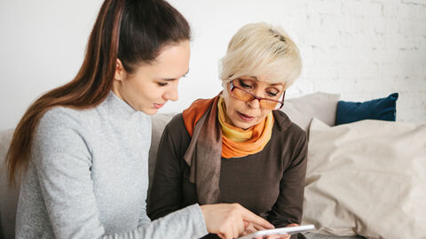 Junges Mädchen erklärt älterer Frau den Umgang mit einem Tablet