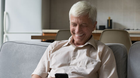 Älterer Mann schaut auf sein Smart-Telefon