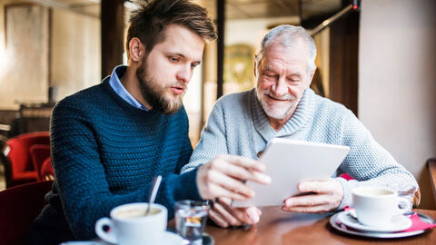 Jüngerer Mann erklärt älteren Mann Tablet