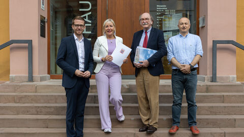 Digitalministerin Sinemus bei der Übergabe eines Förderbescheids in Lauterbach. Sie steht mit drei Herren auf einer Treppe vor einem Gebäude.