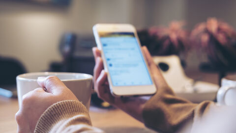 Mann surft mit seinem Handy bei einem Kaffee im Internet.