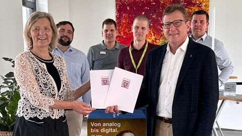 Förderung Starke Heimat Hessen für den Landkreis Gießen Staatssekretär Stefan Sauer übergibt einer Dame den Zuwendungsbescheid, im Hintergrund mehrere weitere Personen.