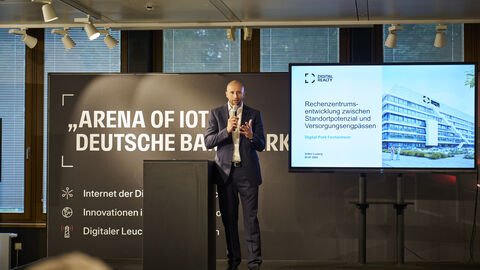 Ein Mann steht auf der Bühne mit einem Mikrofon in der Hand.