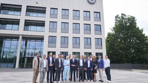 Eine Gruppe über 10 Menschen stehen vor dem Gebäude von Eintracht Frankfurt.