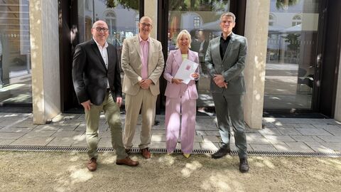 Dr. Sinemus steht mit drei Männern in einer Reihe - sie hält einen Förderbescheid in den Händen.