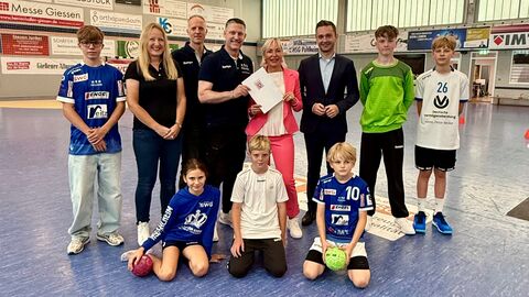 Digital Handball 2026 Mehrere Erwachsene und Kinder stehen in Handballhalle.