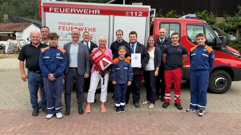 Mehrere Personen stehen vor Feuerwehrauto.