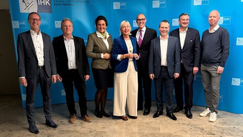 „Innovation meets Finance“ in Kassel Digitalministerin Sinemus steht mit einer Gruppe vor einem Aufsteller der IHK.