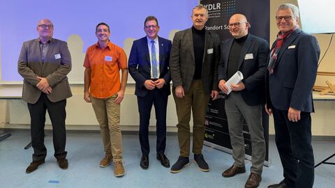 Sechs Männer stehen nebeneinander. Hinter ihnen ein Aufsteller mit der Aufschrift "KDLR".